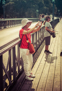 Side view of friends standing on footbridge