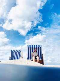 Low angle view of hooded chairs on beach against sky
