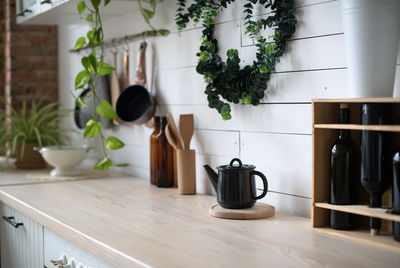 A black kettle and potted plant on table at kitchen 