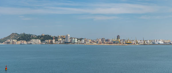 Sea by city buildings against sky