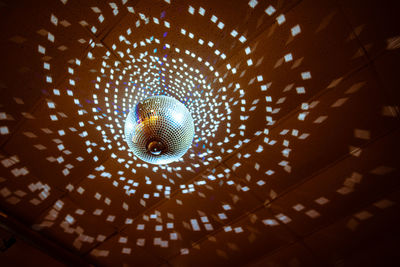 Low angle view of illuminated disco ball hanging from ceiling in nightclub