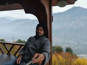 Young man using smart phone against mountains