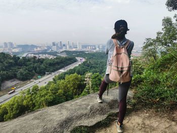 Rear view of woman standing on rock against sky