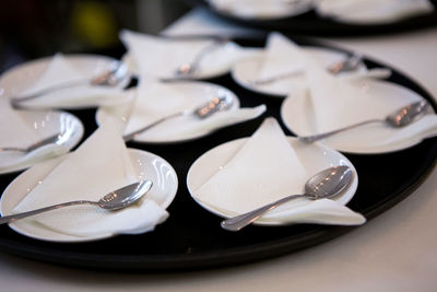 Lot white plates, saucers , spoons and paper napkins on a tray for cake, dessert