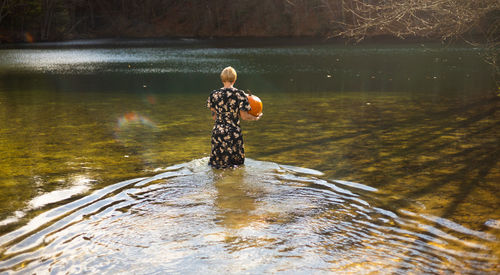 Rear view of woman standing in lake