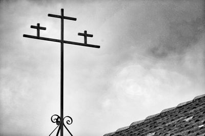 Low angle view of cross on pole against sky