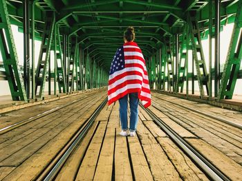 Rear view of woman with american flag standing on footbridge