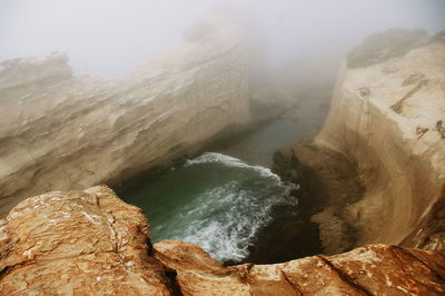 High angle view of sea and cliffs during foggy weather