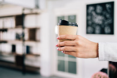 Close up woman barista hand serving coffee paper disposable cup in the coffee shop. 