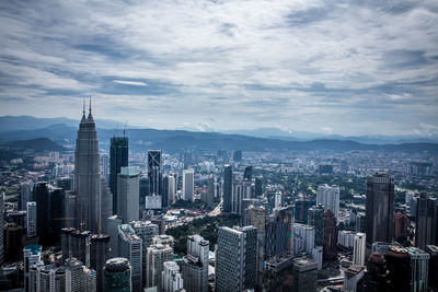 Aerial view of cityscape against cloudy sky