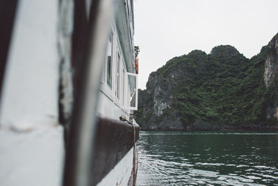 Ship sailing on sea against mountain