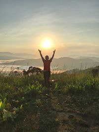 Man standing on field against sky during sunset