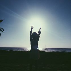 Girl standing at beach against sky