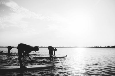 Men standing on sea shore against sky