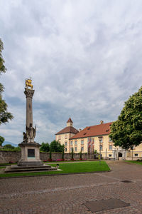 Statue by building against sky