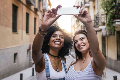 Smiling friends talking selfie in city