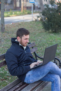 Rear view of man using mobile phone outdoors