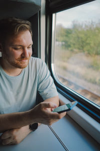 A man using a smartphone while traveling by railway train