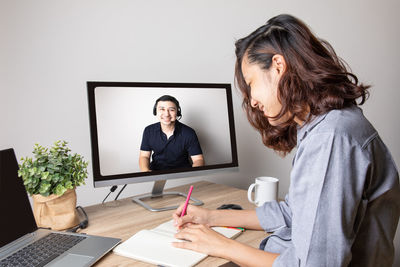 Woman using phone while sitting on table