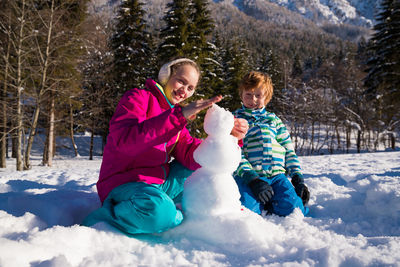 Smiling women standing on snow covered trees during winter