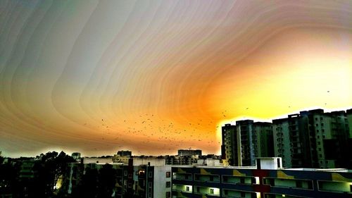 Cityscape against dramatic sky during sunset