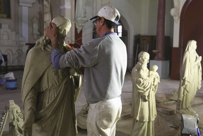 Sculptor making jesus christ statue in workshop