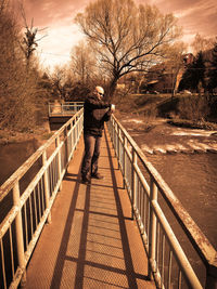 Man walking on footpath amidst bare trees