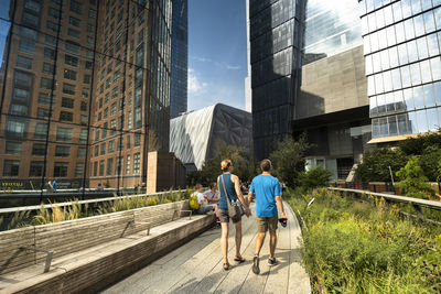 People walking on modern glass building in city