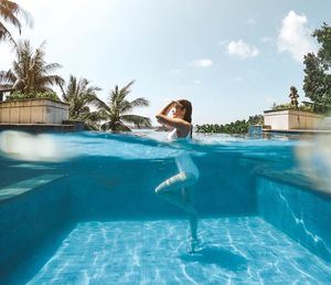 Woman swimming in pool against blue sky