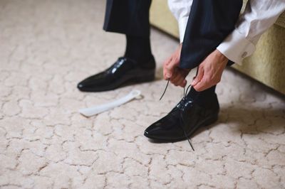 Low section of man tying shoelace at home