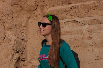 Pretty hiker girl with traveling backpack moving up on mountain road. smiling traveler  looks away.