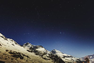 Low angle view of snowcapped mountain against sky at night