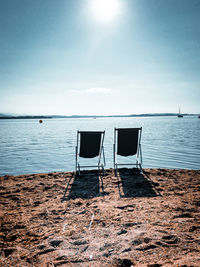 Chair on beach against sky