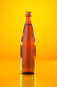 Close-up of glass bottle against yellow background