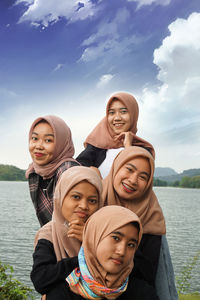 Portrait of smiling friends against sky