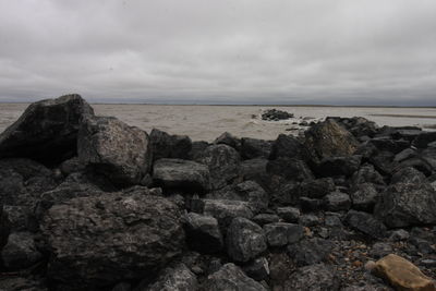 Rocks on sea shore against sky