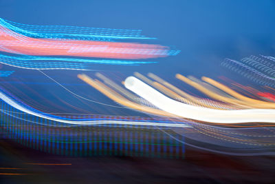 Multi colored light trails on bridge in city at night