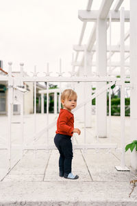 Full length of cute boy standing against built structure