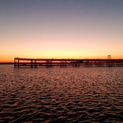 Bridge over sea against clear sky during sunset