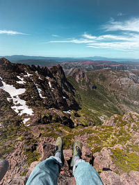 Low section of person on rock against sky