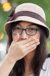 Close-up portrait of young woman covering mouth