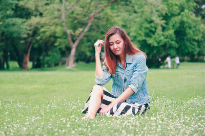 Young woman using phone while sitting on grass