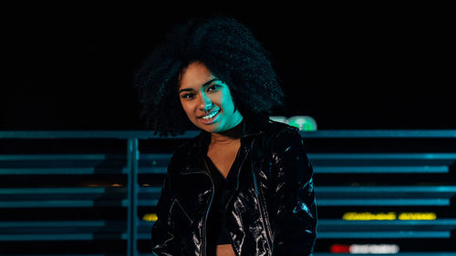 Portrait of smiling young woman sitting outdoors at night