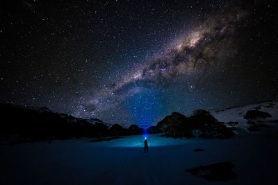 Rear view of man standing against star field at night