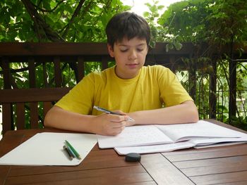 Boy studying at table in porch