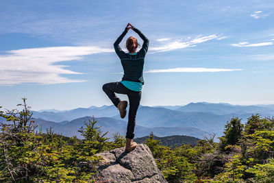 Full length of person with arms raised against sky