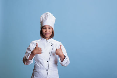 Portrait of young woman standing against blue background