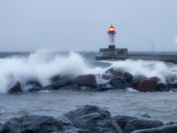 Lighthouse by sea against clear sky
