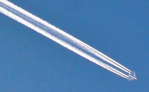 Low angle view of vapor trails in blue sky