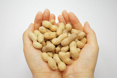 Close-up of hand holding bread against white background